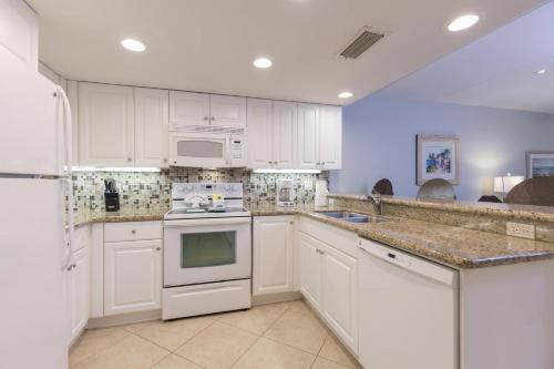 una cocina con armarios blancos y electrodomésticos blancos en Surfside II #109 home, en Coffeyville