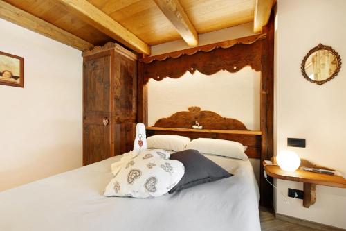 a bedroom with a white bed with a wooden headboard at Appartamenti Cucu - 1 in Lillianes
