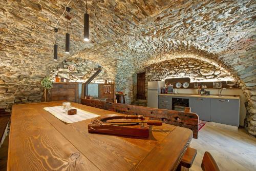 a wooden table in a kitchen with a stone wall at Appartamenti Cucu - 1 in Lillianes