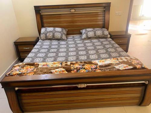 a large bed with a wooden headboard and pillows at Bahria Villa in Karachi