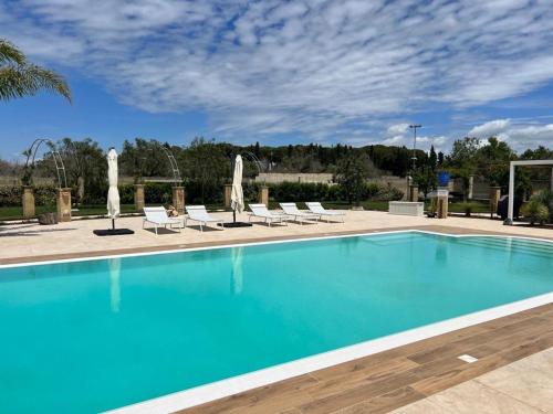 a swimming pool with chairs and a blue pool at Villa Anna - Suites & Events in Specchia