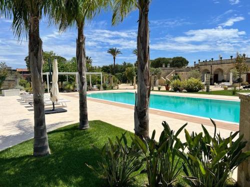 a villa with a swimming pool with palm trees at Villa Anna - Suites & Events in Specchia