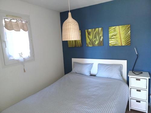 une chambre avec un lit et un mur bleu dans l'établissement Plain-pied Jardin 6 personnes Clim Vue Mer Parking Wifi Terrasse Piscine dans la résidence, à Saint Pierre La Mer