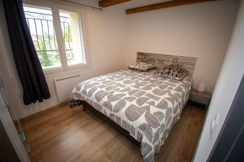 a bedroom with a bed with a comforter and a window at Appartement de 2 chambres avec piscine partagee jacuzzi et jardin clos a Avignon in Avignon