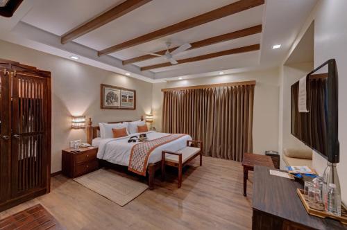 a bedroom with a bed and a flat screen tv at The Fern Gir Forest Resort, Sasan Gir - A Fern Crown Collection Resort in Sasan Gir