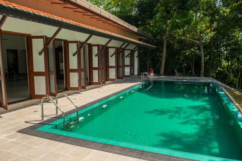a swimming pool in front of a house at Minnehaha Bentota in Bentota