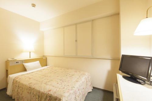 a hotel room with a bed and a flat screen tv at Green Hotel Kitakami in Kitakami