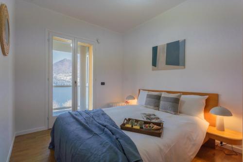 a bedroom with a large white bed with a window at Besana 9 on the Lake - Private garden & parking by Rent All Como in Moltrasio