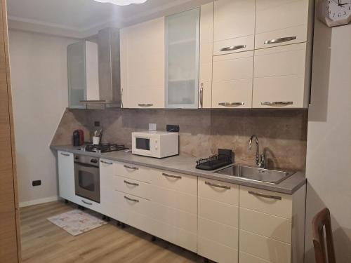 een keuken met witte kasten, een wastafel en een magnetron bij The Green House in Troghi in Troghi