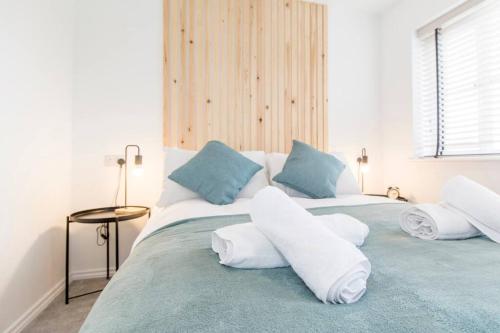 Captivating 3-Bedroom House with Netflix and Parking by HP Accommodation في Kibworth Harcourt: غرفة نوم بسرير كبير مع شراشف بيضاء ومخدات زرقاء