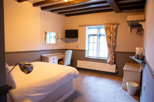 a bedroom with a white bed and a window at Ye Old Boote Inn in Whittington