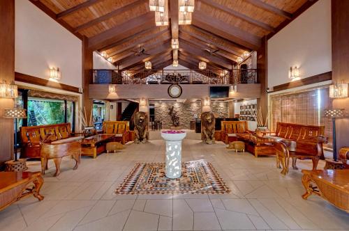 a large lobby with wooden furniture and a clock at The Fern Gir Forest Resort, Sasan Gir - A Fern Crown Collection Resort in Sasan Gir