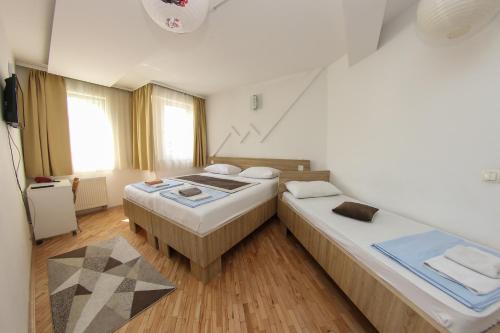 two beds in a room with wooden floors and windows at Hotel Hayat in Sarajevo