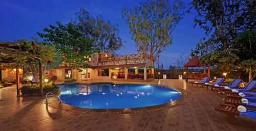 uma piscina com espreguiçadeiras e um edifício em The Fern Gir Forest Resort, Sasan Gir - A Fern Crown Collection Resort em Sasan Gir