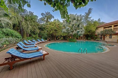 a row of lounge chairs next to a swimming pool at The Fern Gir Forest Resort, Sasan Gir - A Fern Crown Collection Resort in Sasan Gir