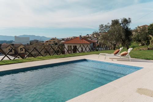 a swimming pool with two chairs and a house at Feel Discovery Casal do Temporao Douro Valley in Peso da Régua