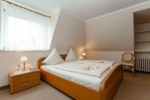 - une chambre avec un lit doté de draps blancs et d'une chaise dans l'établissement Jule im Haus Wega, à Westerland