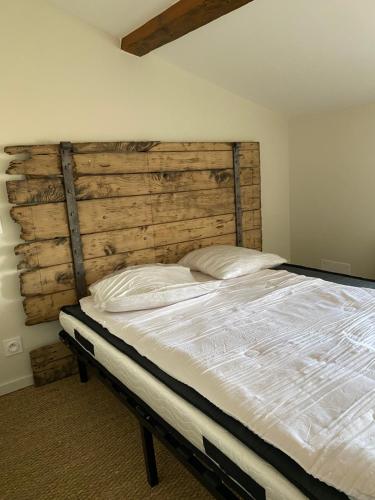une chambre avec un grand lit avec une tête de lit en bois dans l'établissement Chambre 2, à Oudon