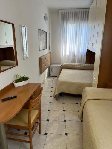 a hotel room with two beds and a desk at Hotel Touring in Sottomarina