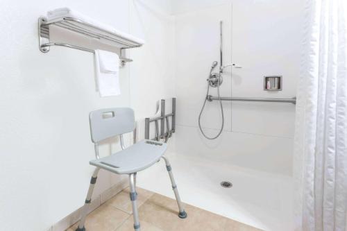 a white shower with a chair in a bathroom at Super 8 by Wyndham Sacramento in Sacramento