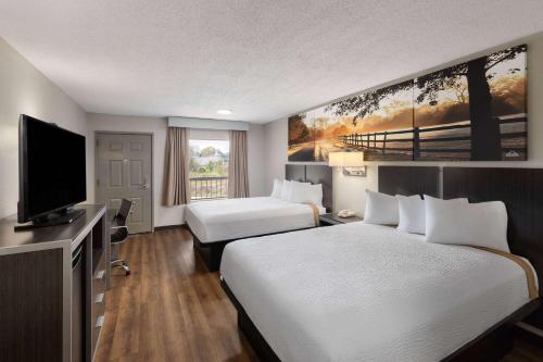 a hotel room with two beds and a flat screen tv at Days Inn by Wyndham Childersburg in Childersburg