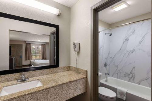 a bathroom with a sink and a shower and a mirror at Days Inn by Wyndham Childersburg in Childersburg