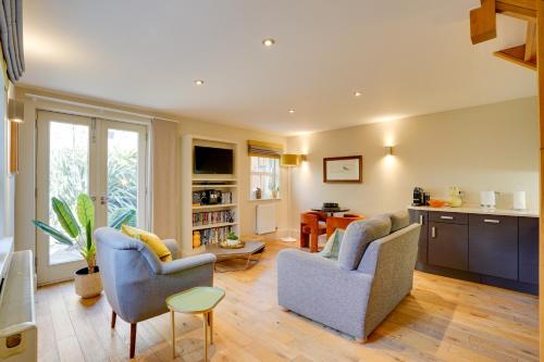 uma sala de estar com duas cadeiras e uma cozinha em Garden Stable at Hallsteads: Luxury Stone Cottage, with Parking em Alnmouth