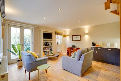 a living room with two chairs and a kitchen at Garden Stable at Hallsteads: Luxury Stone Cottage, with Parking in Alnmouth