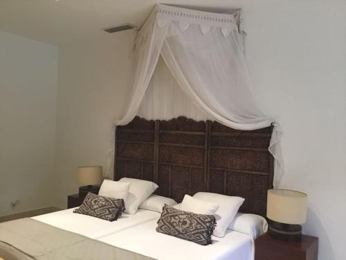 1 dormitorio con cama con dosel y almohadas en Chalet moderno en Sotogrande costa, en San Roque
