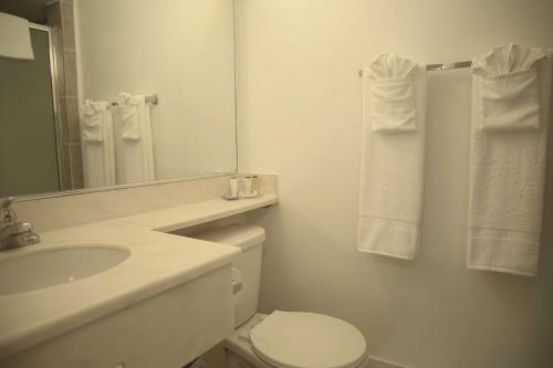 a bathroom with a toilet and a sink and a mirror at Travelodge by Wyndham Burbank-Glendale in Burbank
