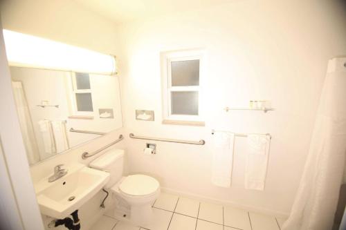 Baño blanco con aseo y lavamanos en Travelodge by Wyndham Burbank-Glendale en Burbank