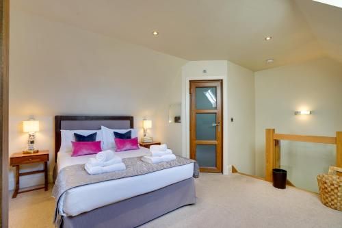 a bedroom with a large bed with pink and blue pillows at Garden Stable at Hallsteads: Luxury Stone Cottage, with Parking in Alnmouth