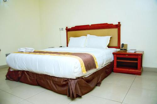 a large bed in a room with a night stand at Classicus Inn & Apartments in Ibadan