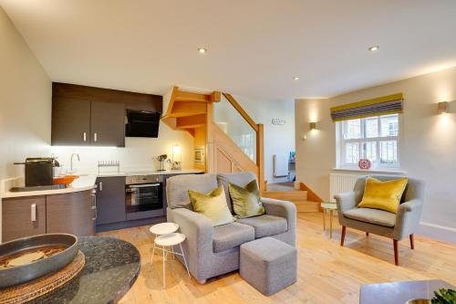 a living room with a couch and chairs and a kitchen at Garden Stable Cosy Stone Cottage with Parking in Alnmouth