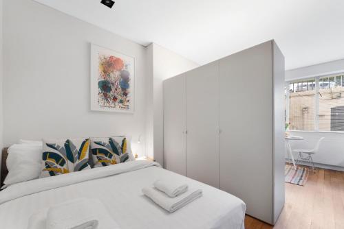 ein weißes Schlafzimmer mit einem großen Bett und einem Badezimmer in der Unterkunft Paddington Studio By Morethanstays in London