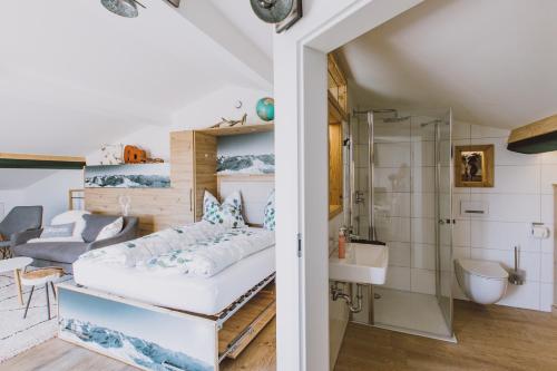 a room with a bed and a bathroom with a shower at Guggi´s Emporeon Allgäu in Germaringen