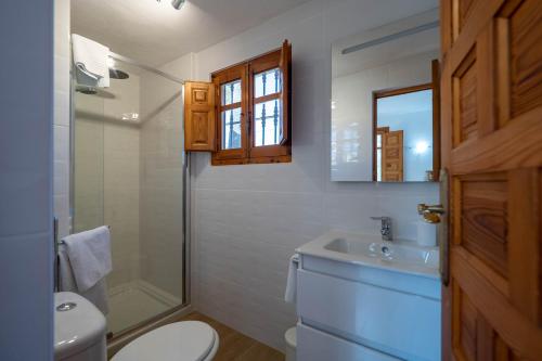 a bathroom with a toilet and a sink and a mirror at Casa Amarilla Casitas in Alhaurín el Grande