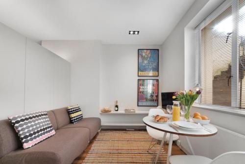 ein Wohnzimmer mit einem Sofa und einem Tisch in der Unterkunft Paddington Studio By Morethanstays in London