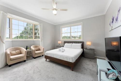 a bedroom with a bed and a tv and two chairs at Aircabin - Blakehurst - Spacious - 5 Beds House in Sydney