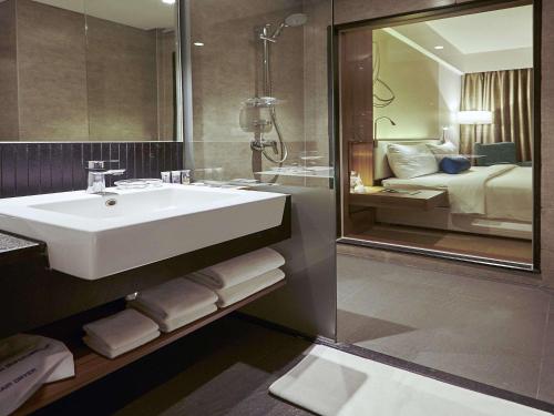 een badkamer met een wastafel, een spiegel en een bed bij Mercure Chennai Sriperumbudur in Sriperumbudur