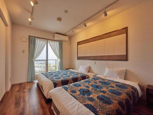 a hotel room with two beds and a window at Yukurina Resort Okinawa in Motobu