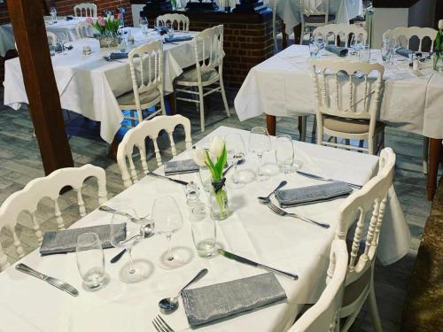 un groupe de tables avec des nappes blanches et des verres dans l'établissement Logis - Hôtel & Restaurant Moulin Des Forges, à Saint-Omer-en-Chaussée