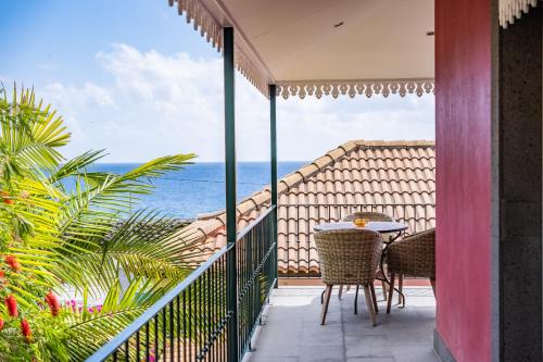 balcón con mesa, sillas y vistas al océano en Quinta da Tia Briosa by Madeira Sun Travel, en Ponta do Sol