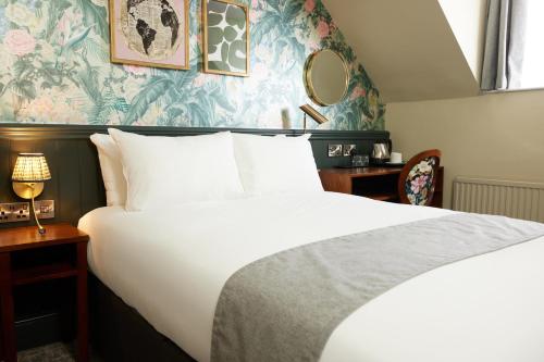 um quarto com uma grande cama branca com papel de parede azul e verde em Narborough Arms em Narborough