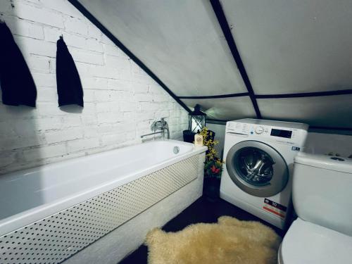 ein Badezimmer mit einer Badewanne und einer Waschmaschine in der Unterkunft LauvasNams in Dubeņi