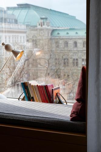 a pile of books on a window sill with a lamp at The Guesthouse Vienna in Vienna
