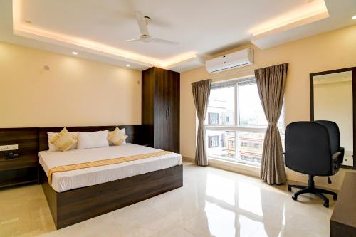 a bedroom with a bed and a desk and a window at AVS Prime in kolkata