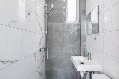 a white bathroom with a shower and a sink at GuestReady - Sunlit Serenity near Montmartre in Paris