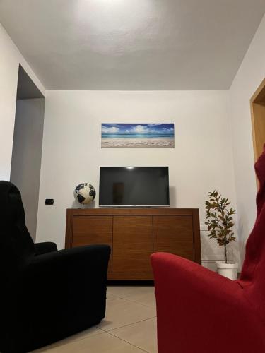 a living room with a tv and a red chair at Sardinia Costa Ovest in Càbras