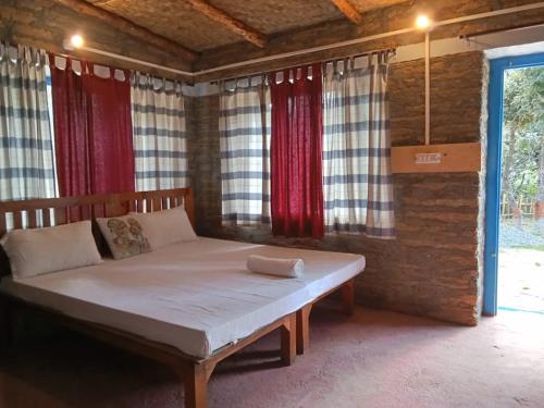 a large bed in a room with red curtains at Glampinn Woods in Nainital